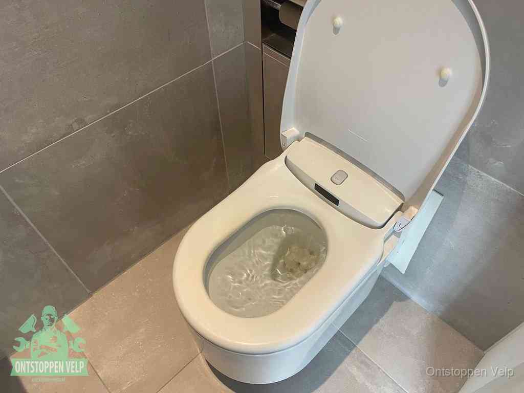 Een toiletpot vol troebel water met drijvend papier en restanten, de meest voorkomende oorzaak van een verstopte wc in Velp