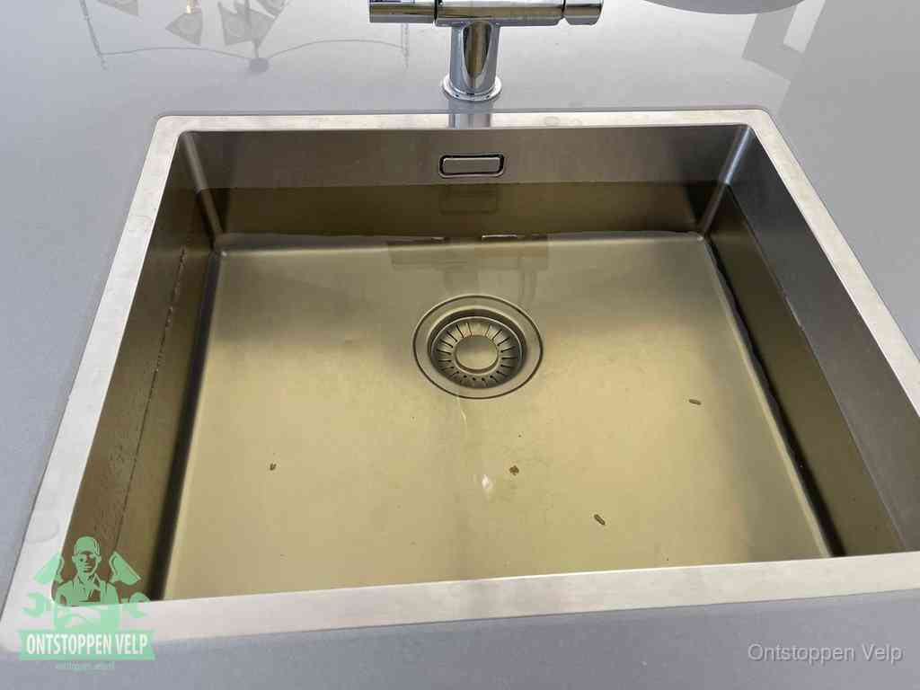 Stilstaand water in een rvs spoelbak dat niet wegloopt, een duidelijk signaal van een gootsteenverstopping in Velp