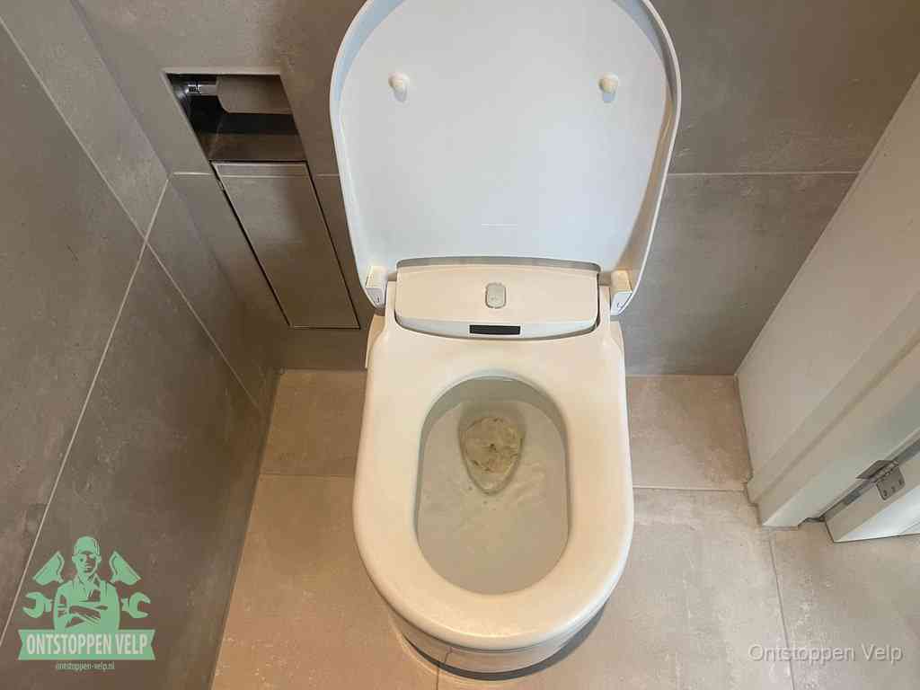 Een wit hangtoilet waarin een prop wc-papier op het water blijft drijven, een duidelijk signaal van een verstopte wc in Velp