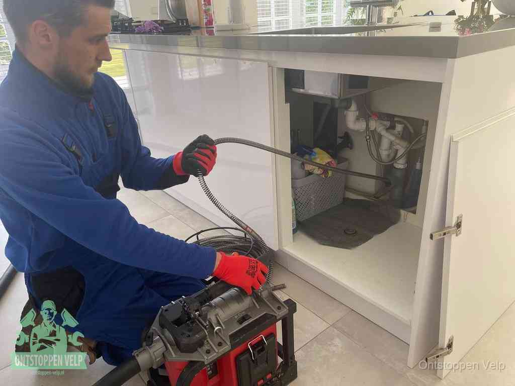 Een monteur reinigt de keukenafvoer grondig met een veermachine om terugkerende gootsteenverstoppingen te voorkomen in Velp