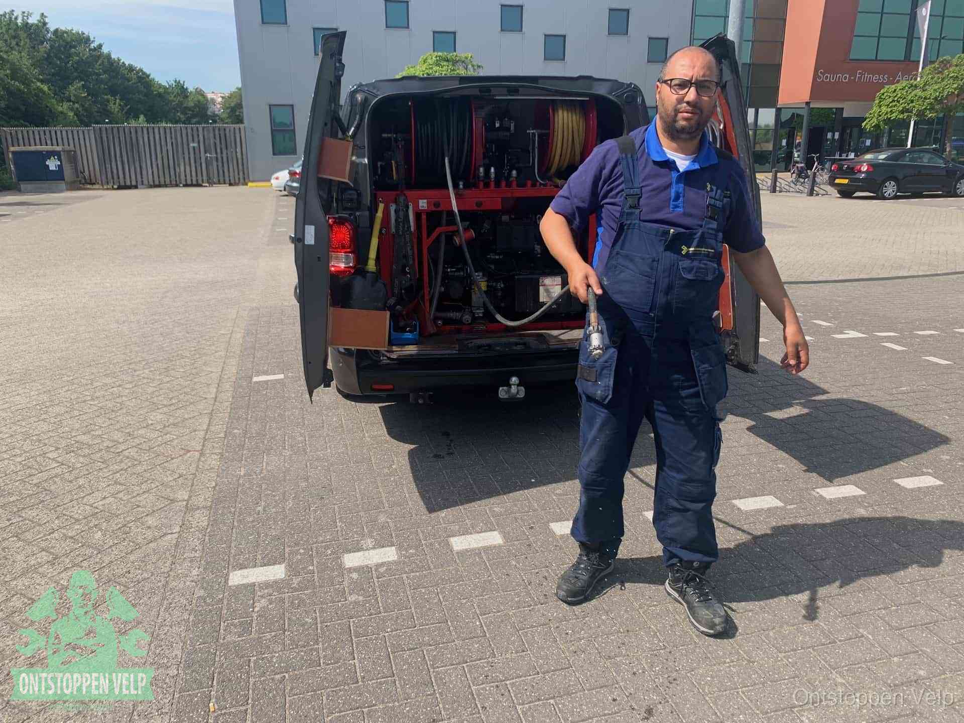 Een monteur bij zijn bestelbus met een hogedruk- en rioolreinigingsunit, klaar om de oorzaak van terugkerende wc-verstoppingen aan te pakken in Velp