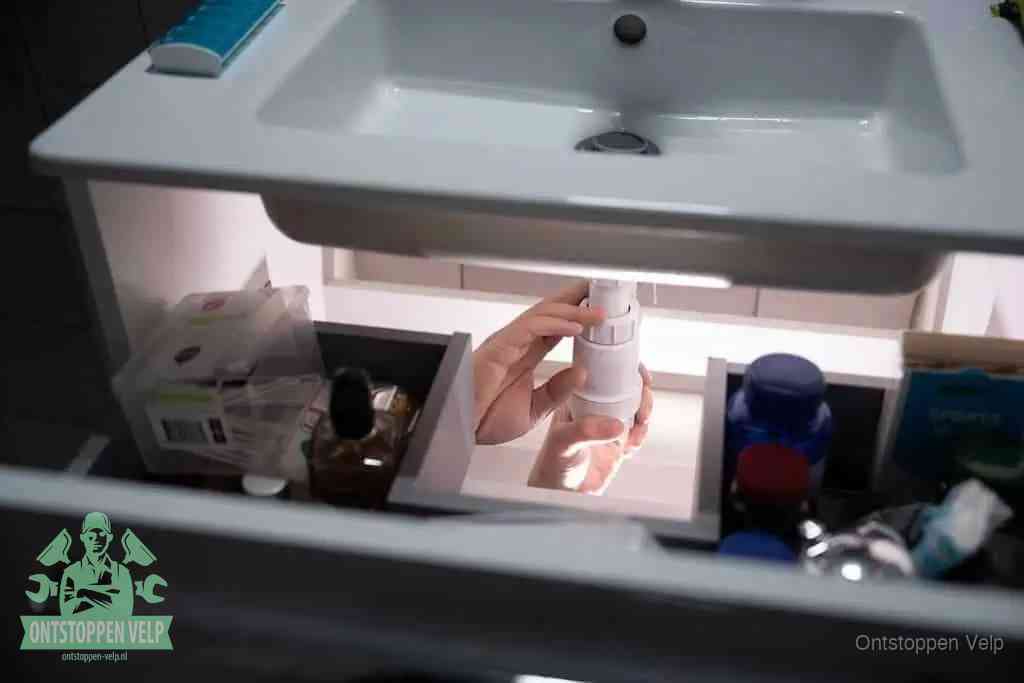 Een pompfles met zeep boven een wastafel in de toiletruimte, de warm water en afwasmiddel-methode om de wc te ontstoppen in Velp