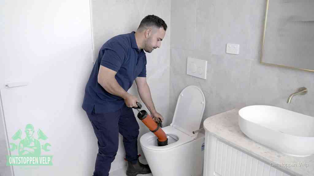 Een monteur gebruikt een handmatige perspomp (toiletontstopper) op een wandcloset tijdens het professioneel wc ontstoppen in Velp
