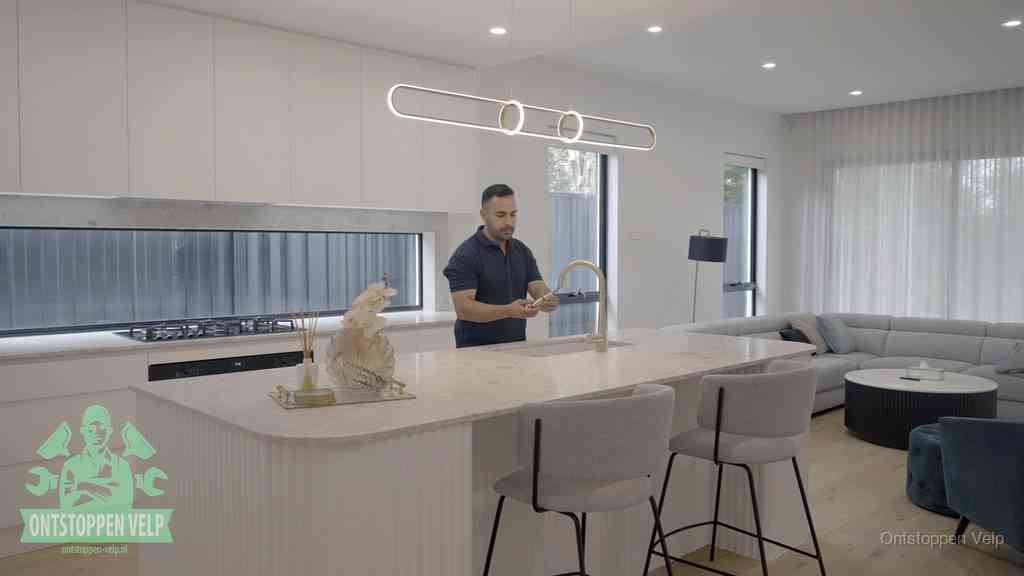 Een bewoner bij de keukenspoelbak die zelf aan de slag gaat met een verstopte gootsteen in Velp